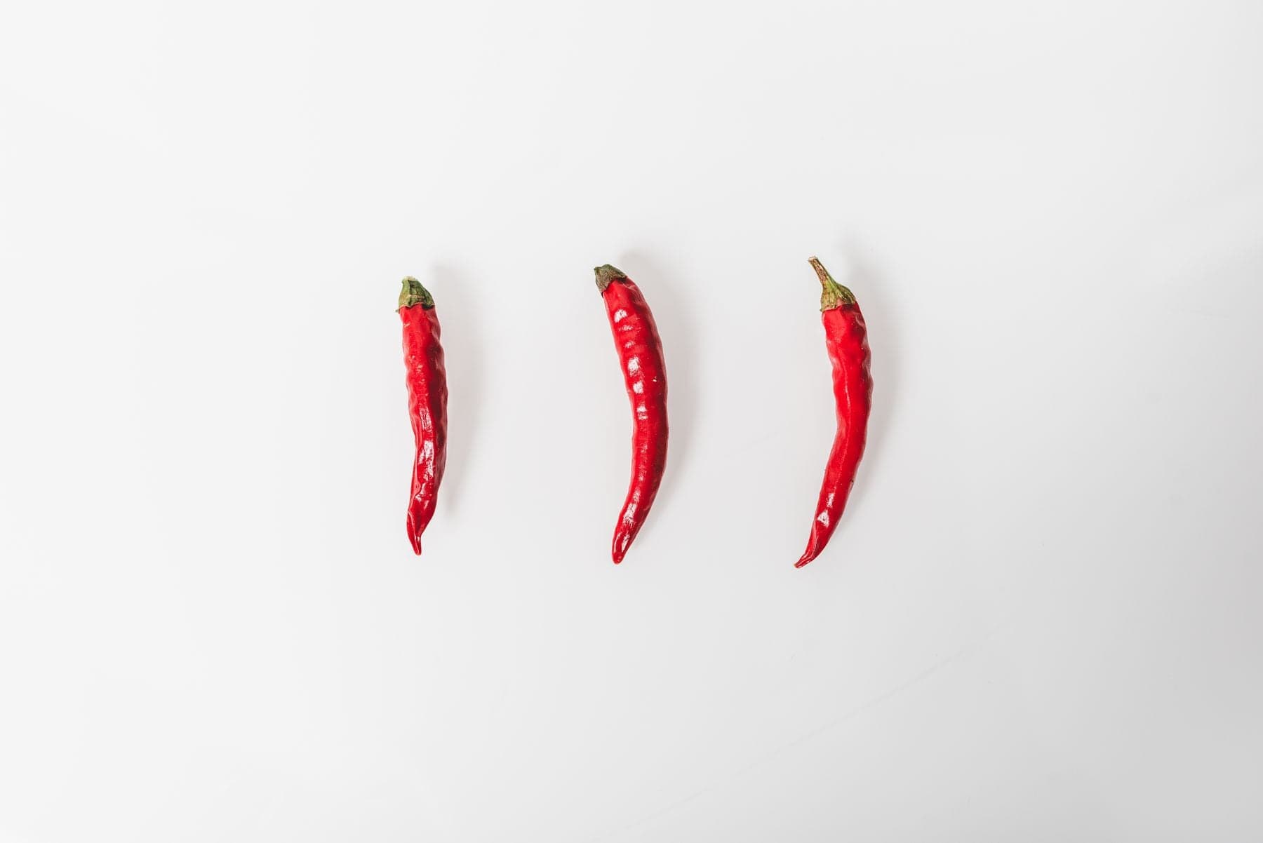 Three small red hot peppers in a row