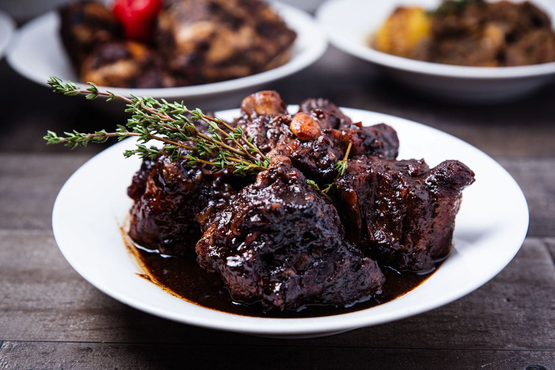 Dark, glossy stewed oxtail topped with a sprig of thyme