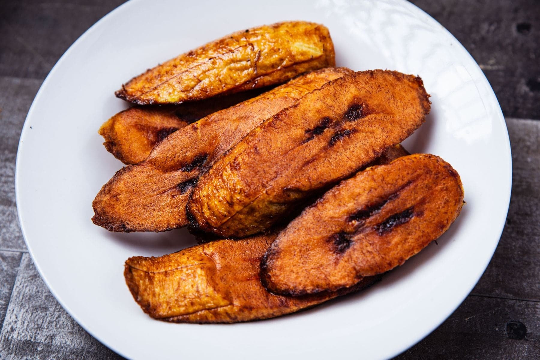 Slices of fried ripe plantain on a white plate