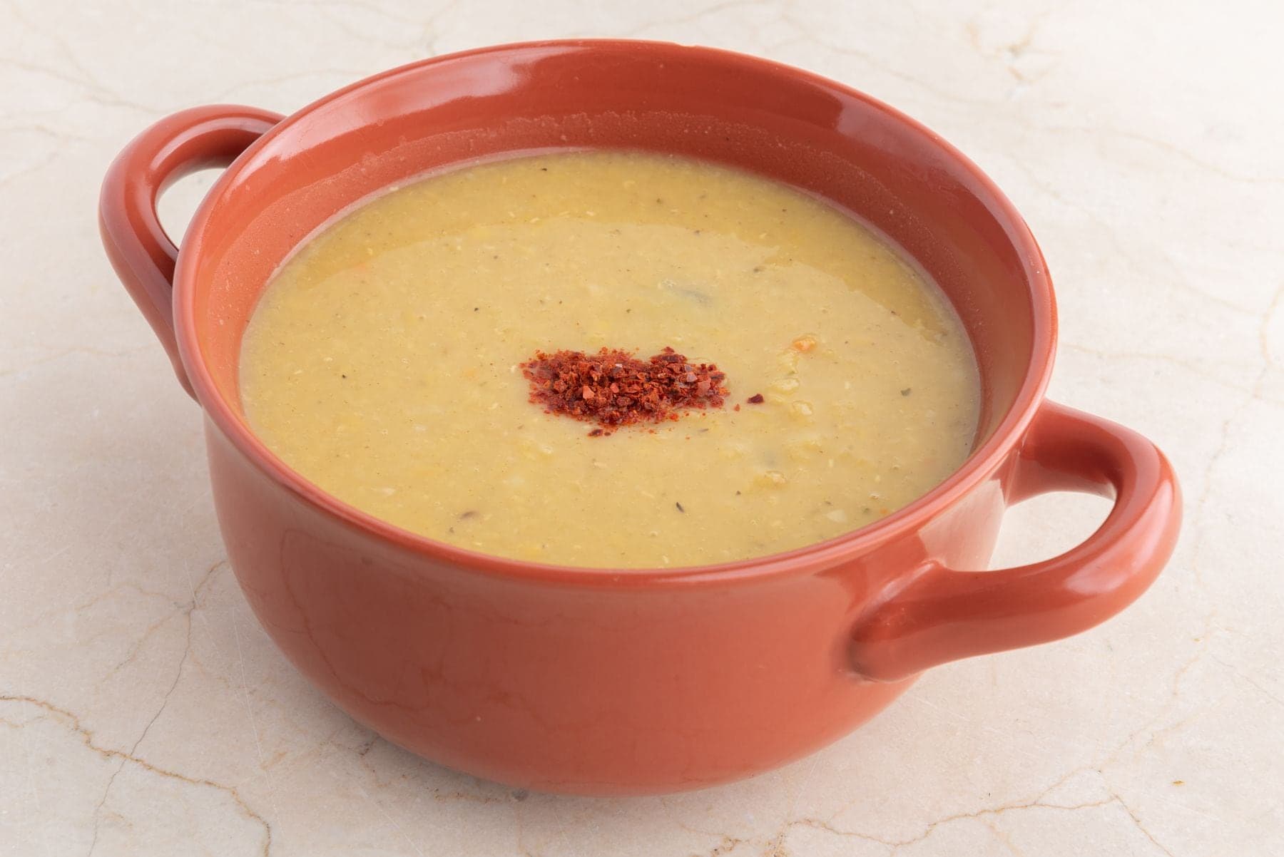 A terracotta pot of smooth yellow soup
