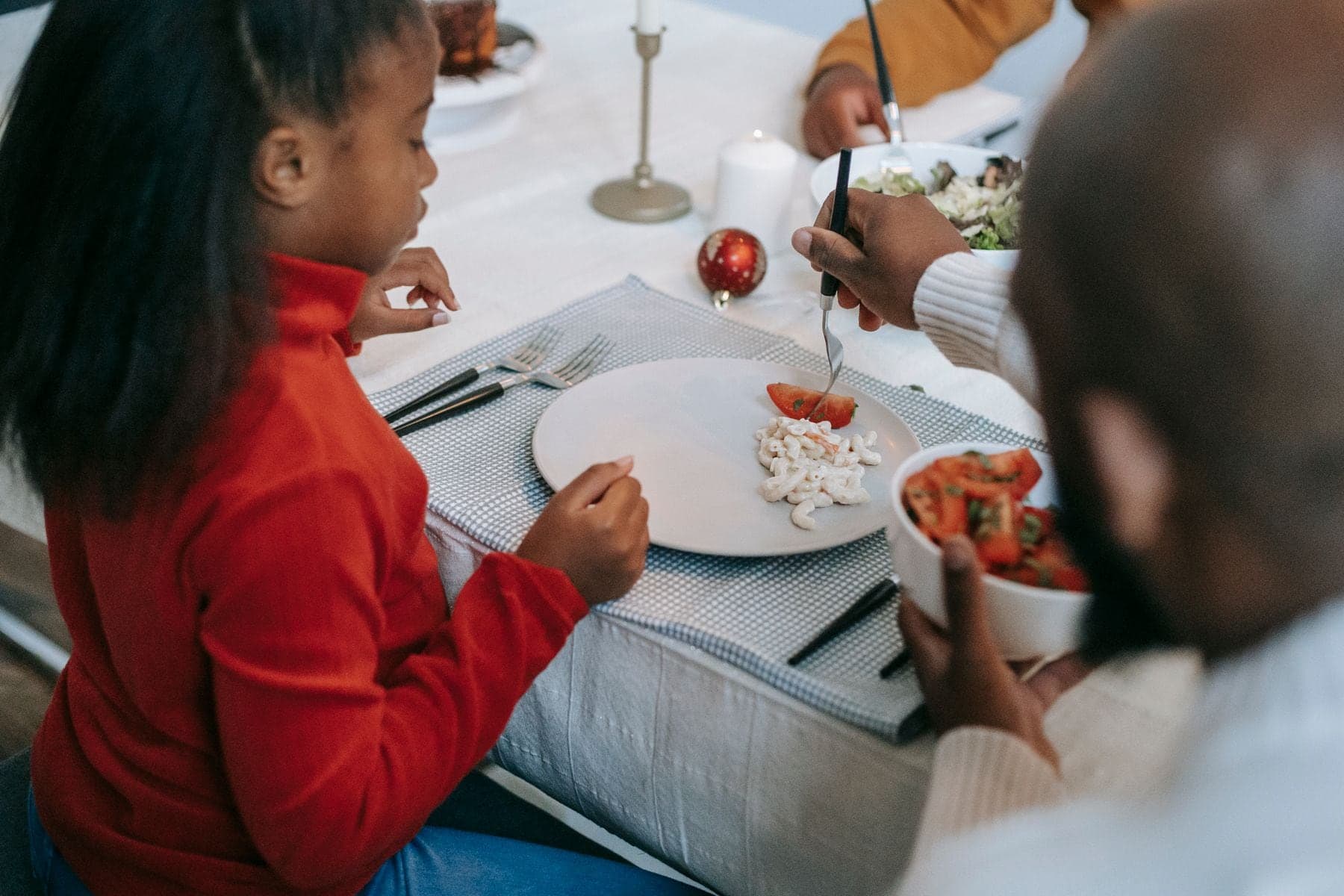 A girl and her father serving themselves at a dinner table