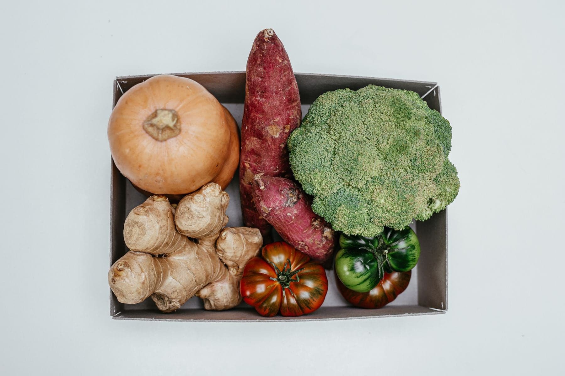 A box packed with squash, sweet potato, ginger, broccoli and tomatoes